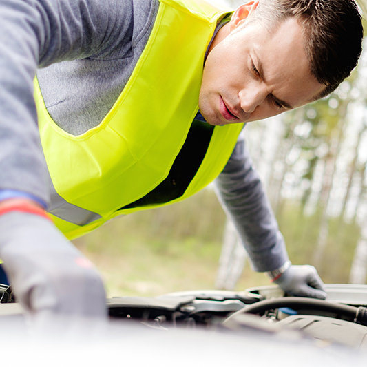 car mechanic checking under the hood on the side of the road